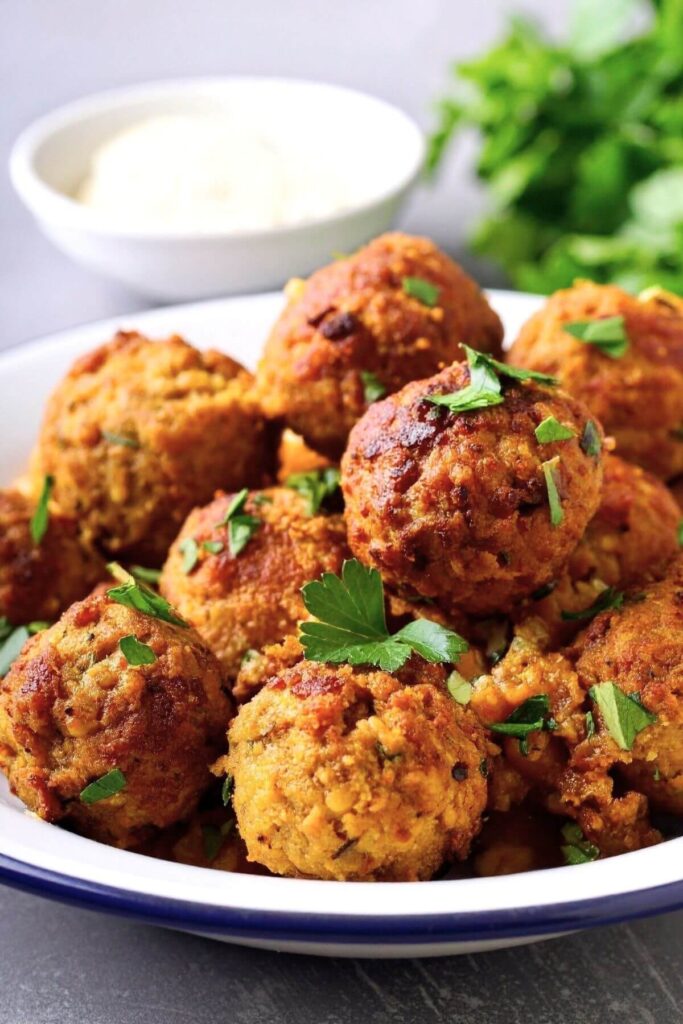 Bowl full of vegan chickpea meatballs garnished with fresh chopped parsley