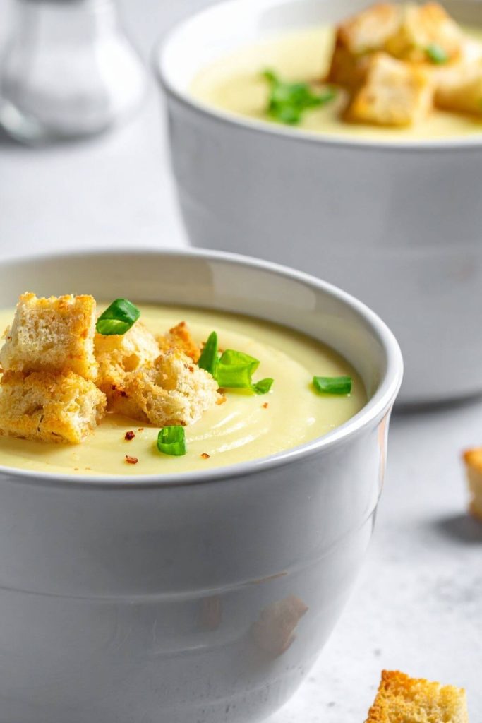 Two bowls of vegan cream of celery soup with croutons