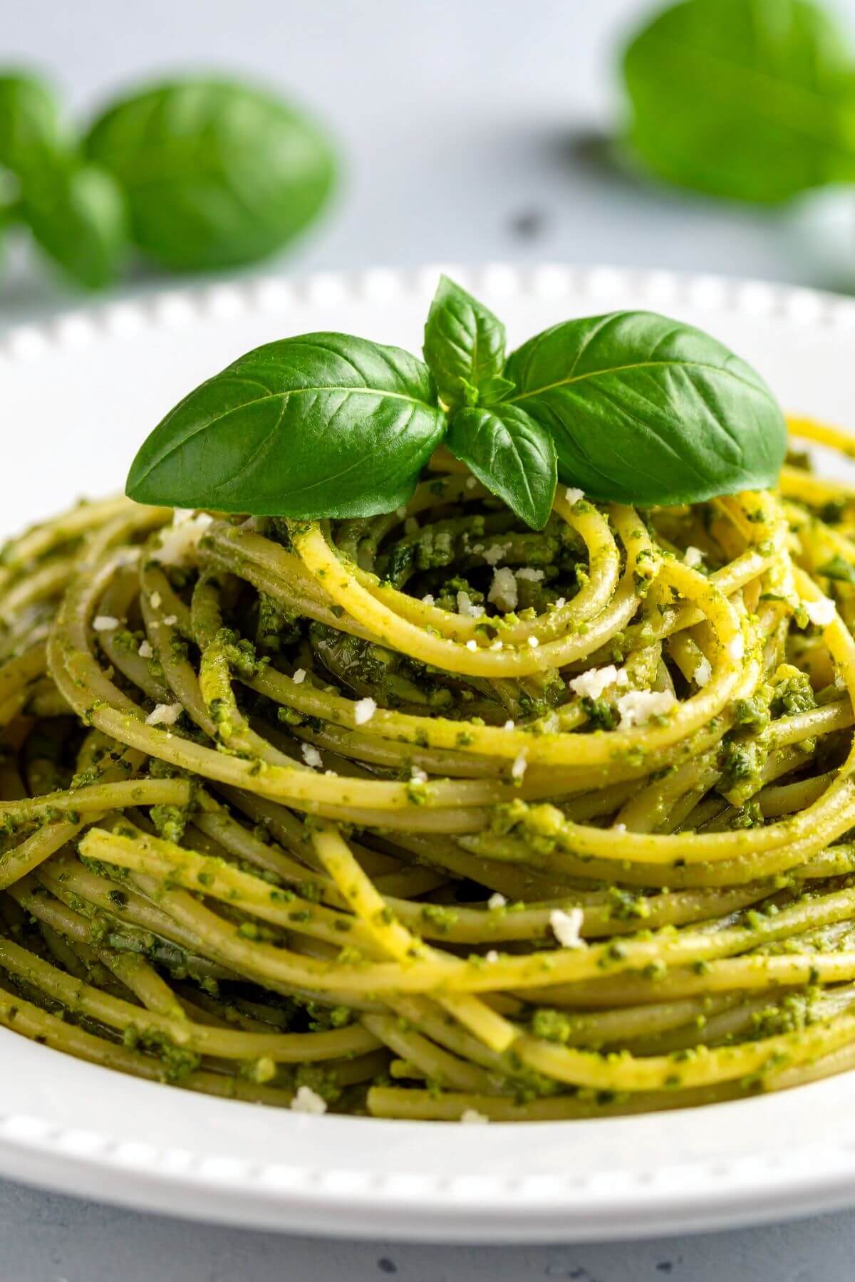 Plate of vegan pesto pasta garnished with basil leaves