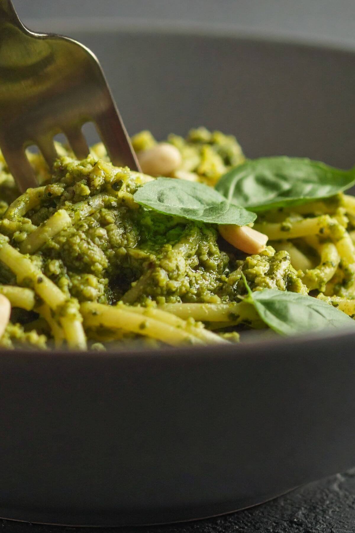 Bowl of vegan pesto pasta garnished with basil leaves