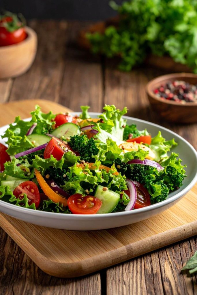 Dish of side salad with lettuce, tomatoes, cucumber and more.