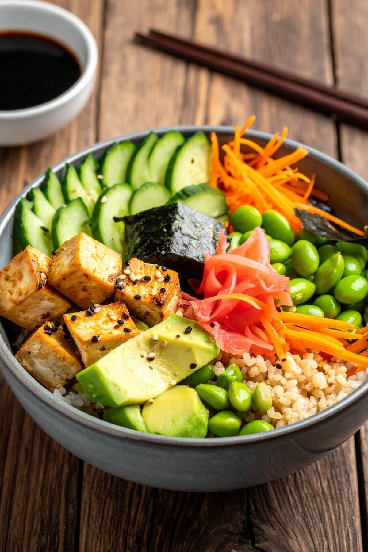 A Vegan Sushi Bowl with Brown Rice, Vegetables, sliced avocados and tofu.