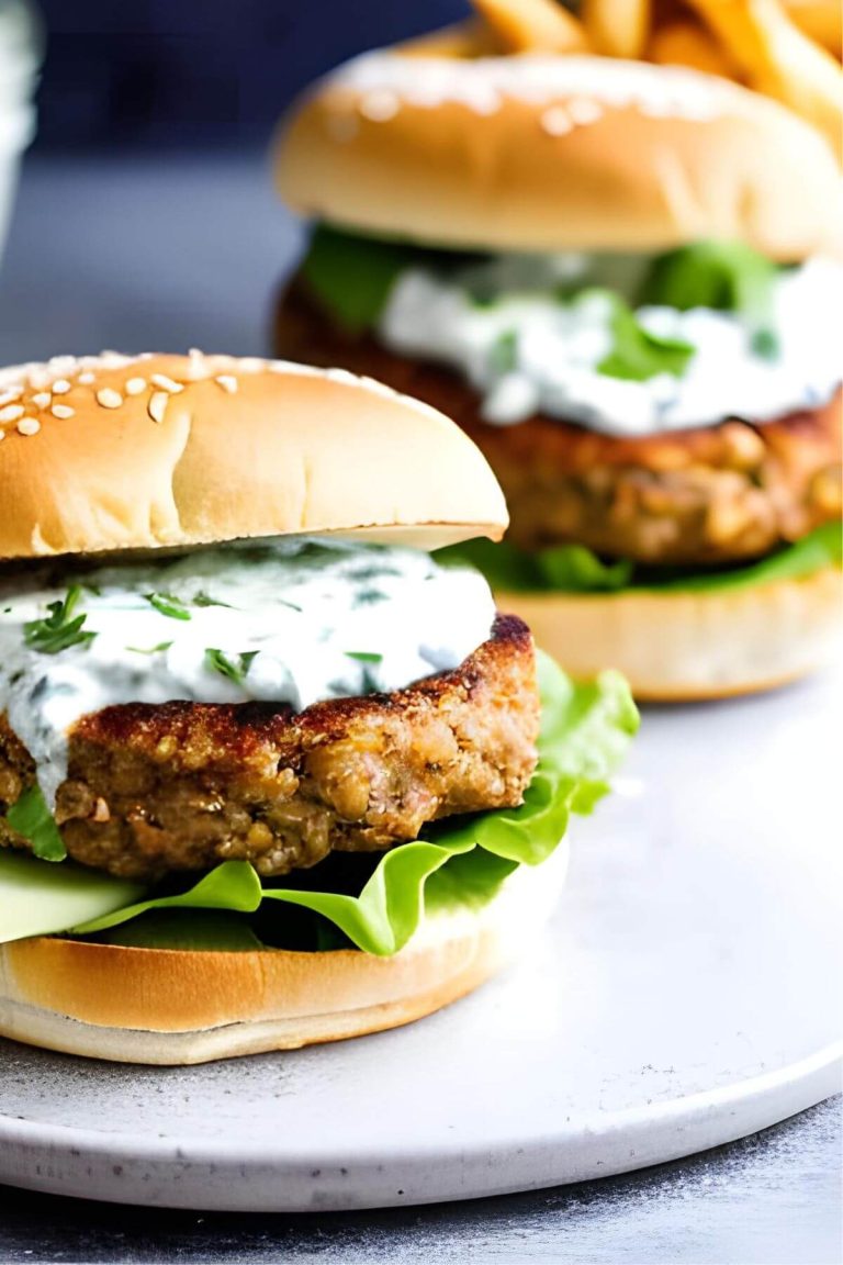 Two Vegan Lentil Burgers on a white plate with lettuce and sauce