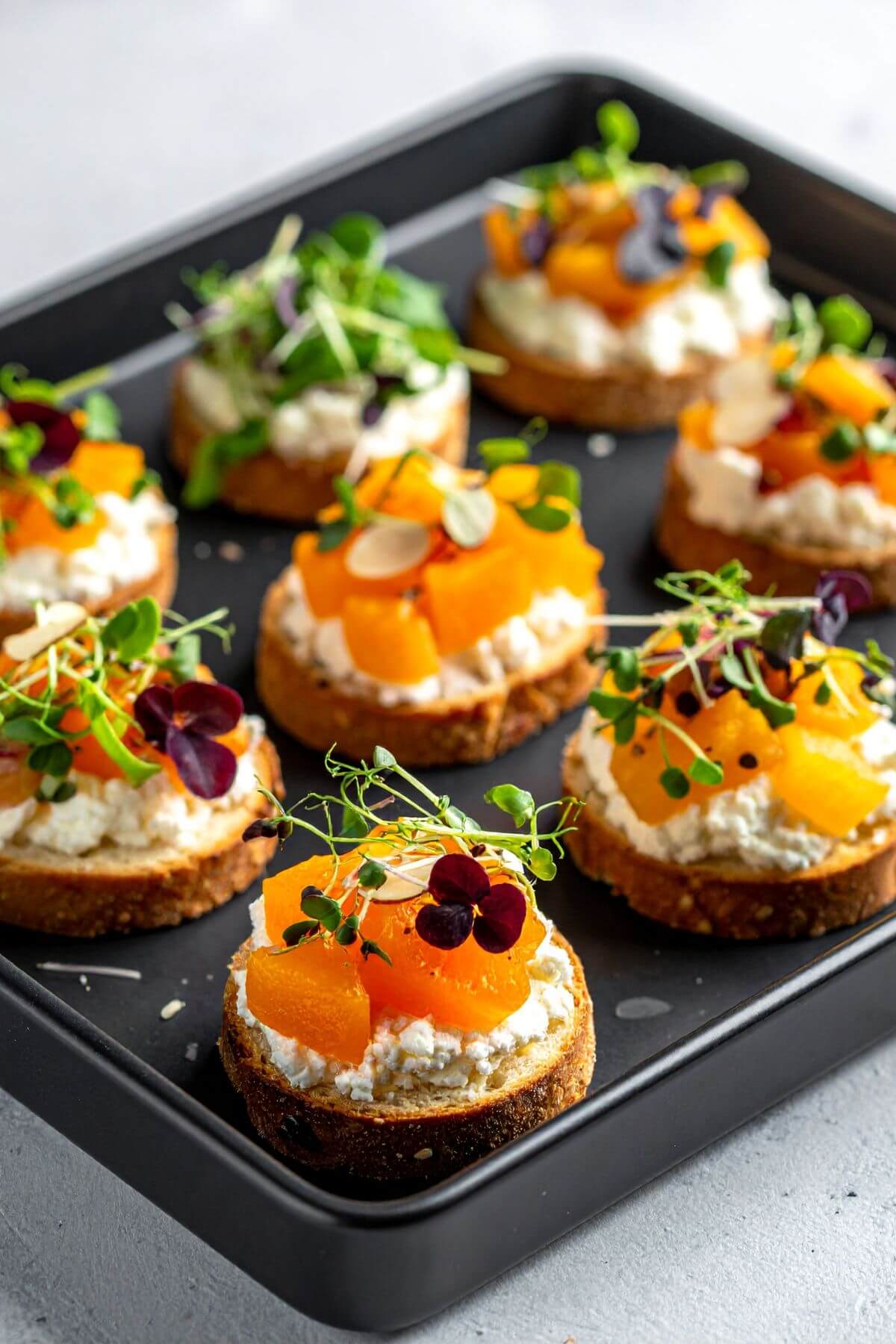 Tray of Apricot, Almond, Vegan Feta Crostini with microgreens
