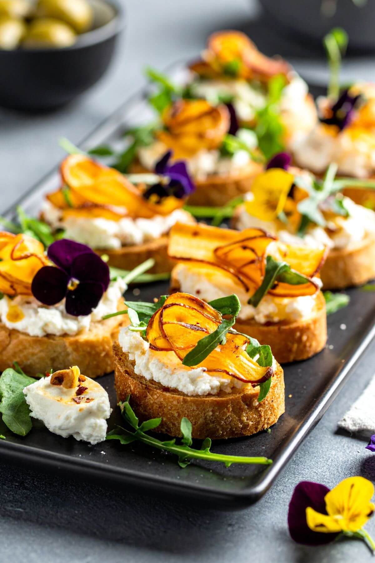 Roasted Parsnips and Garlic Crostini with pansy flower garnish