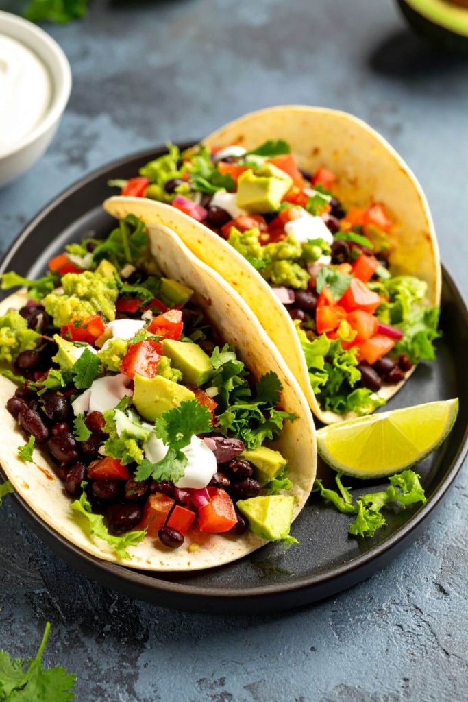 2 classic vegan Black Bean Tacos on a plate with a wedge of lime