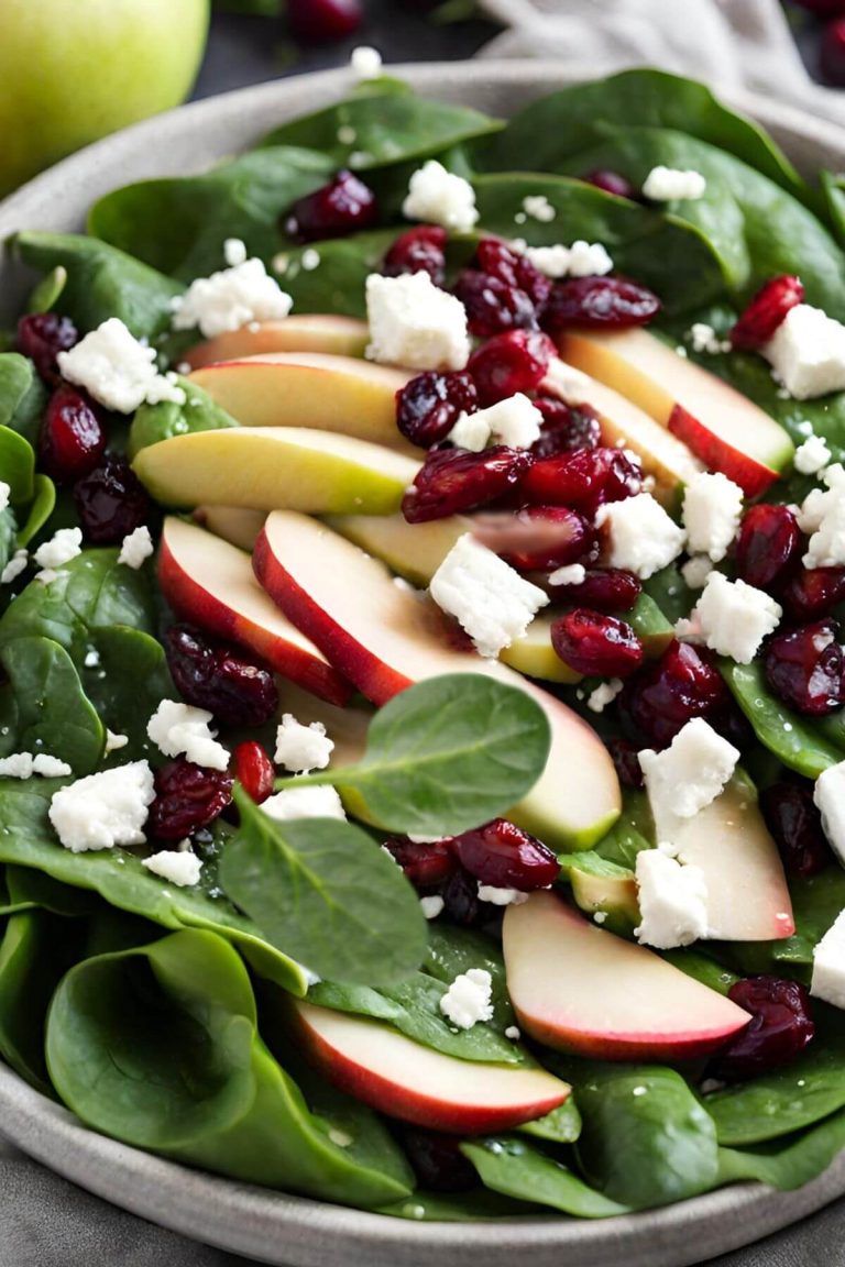 A large bowl of Apple Cranberry Spinach Salad with vegan feta