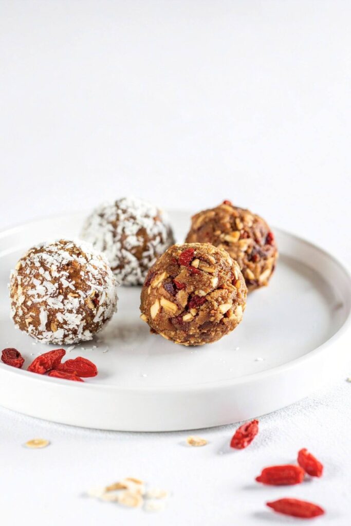 Goji Berry Energy Bites. 2 coated with coconut flakes and 2 uncoated. Goji Berries on the side