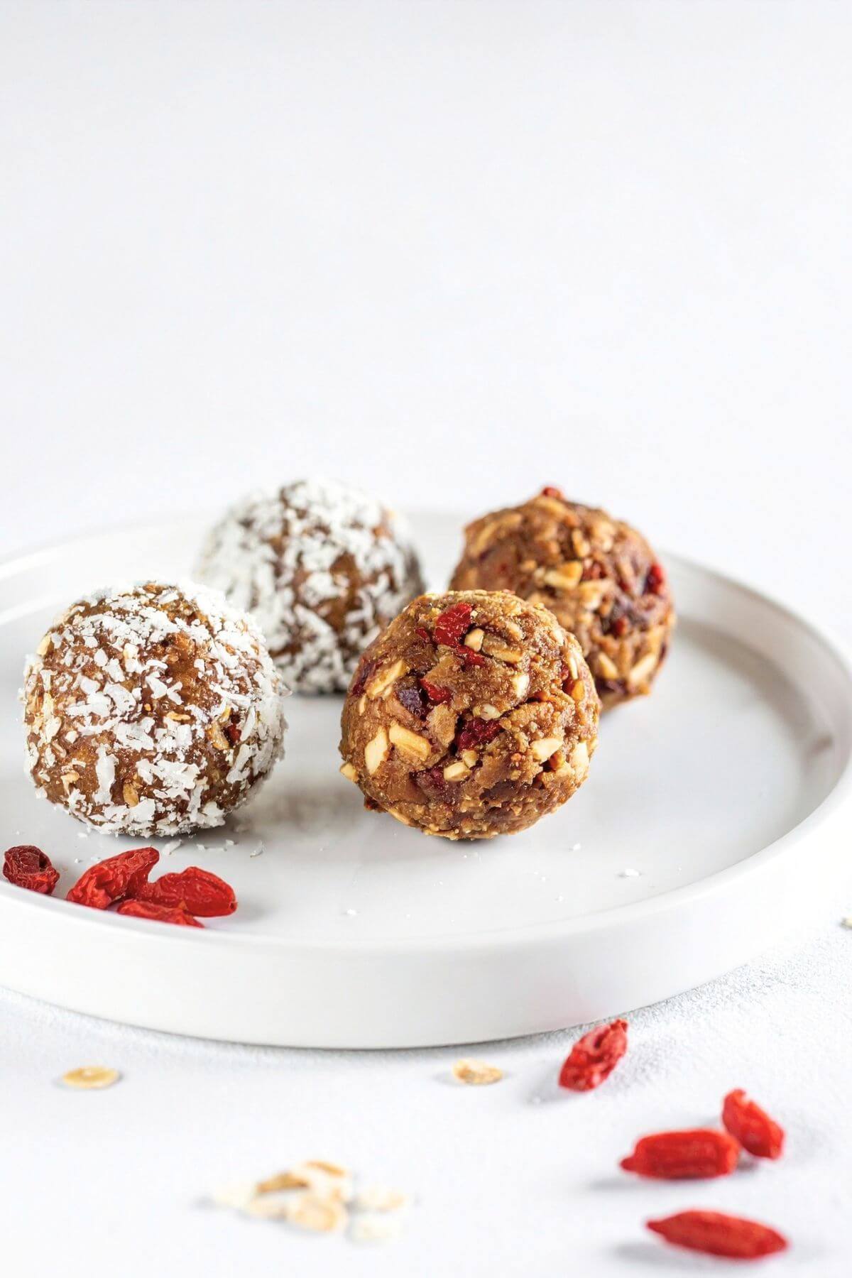 Goji Berry Energy Bites. 2 coated with coconut flakes and 2 uncoated. Goji Berries on the side