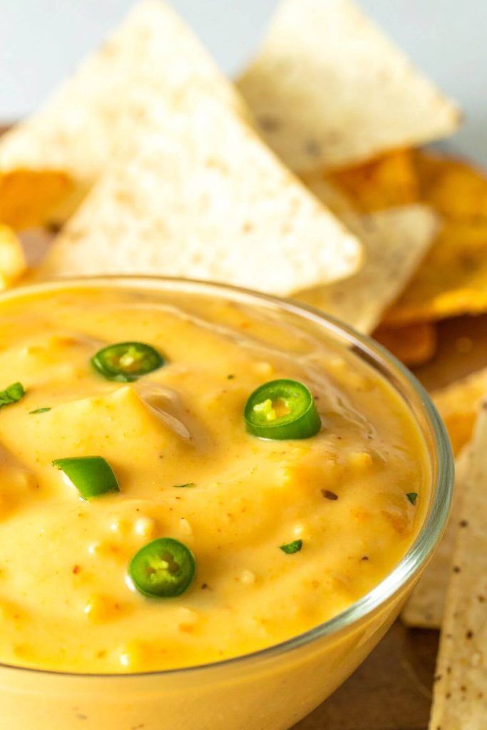 Bowl of Vegan cashew nacho cheese sauce with chips and jalapeno garnish