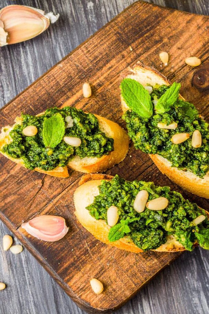 3 Pea Pesto Crostini garnished with pine nuts and mint
