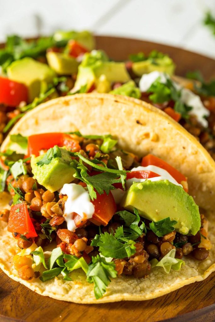 Vegan Lentil tacos with diced tomatoes, avocado. cilantro, vegan sour cream