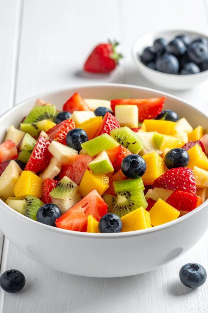 Bowl of delicious fruit salad with blueberries on the side