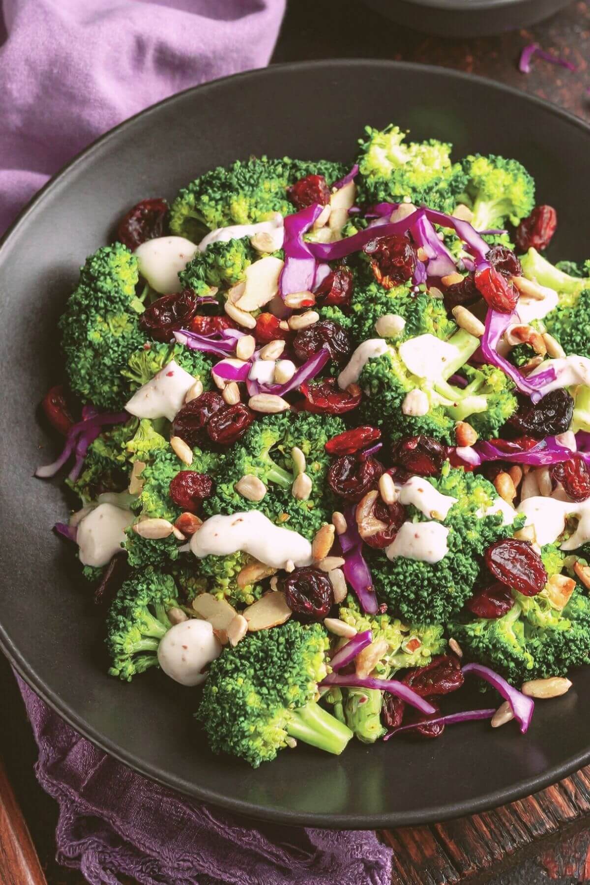 Dish of vegan Broccoli Salad with broccoli, dried cranberry, seeds, almonds and mayo dressing