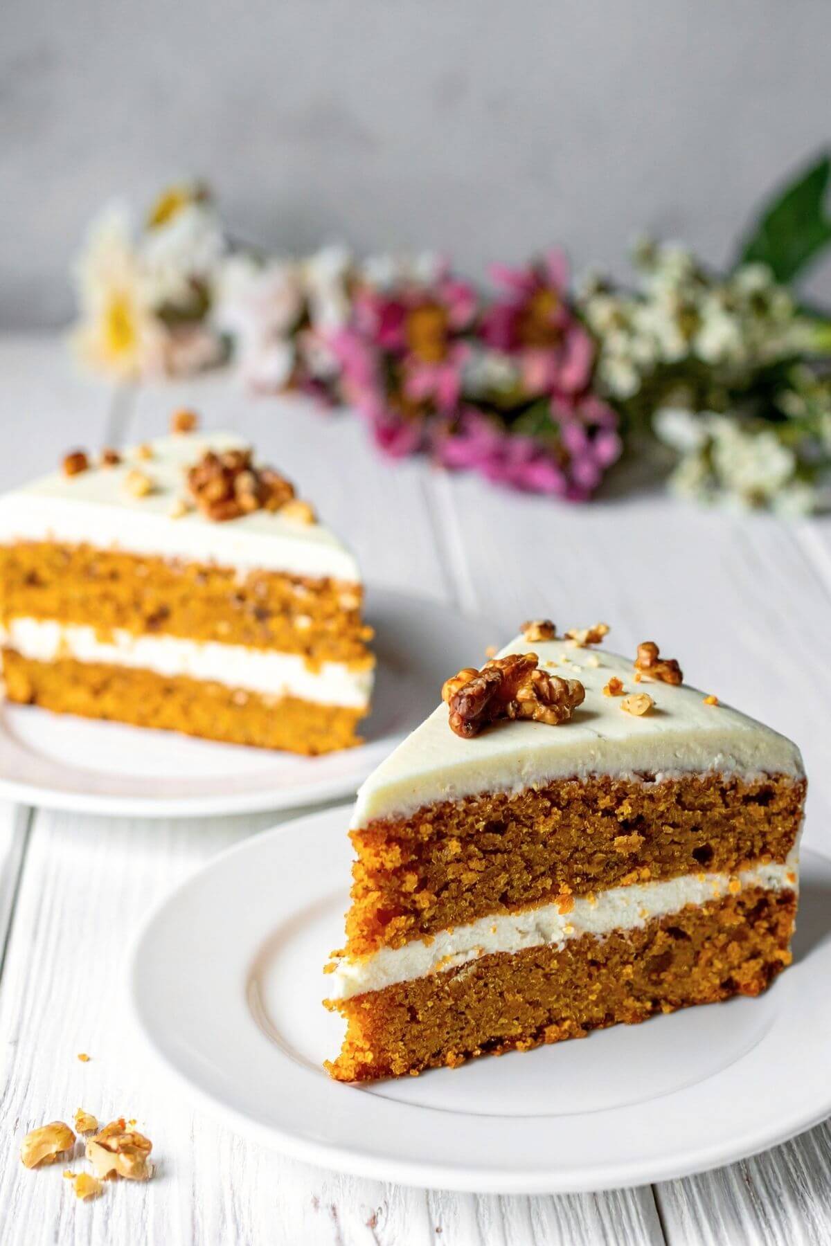 2 slices of vegan carrot cake with cream cheese frosting two layer cake