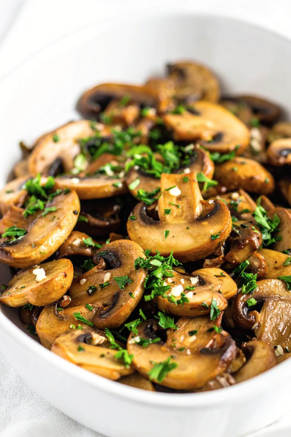 vegan garlic butter mushrooms in a bowl with fresh parsley minced