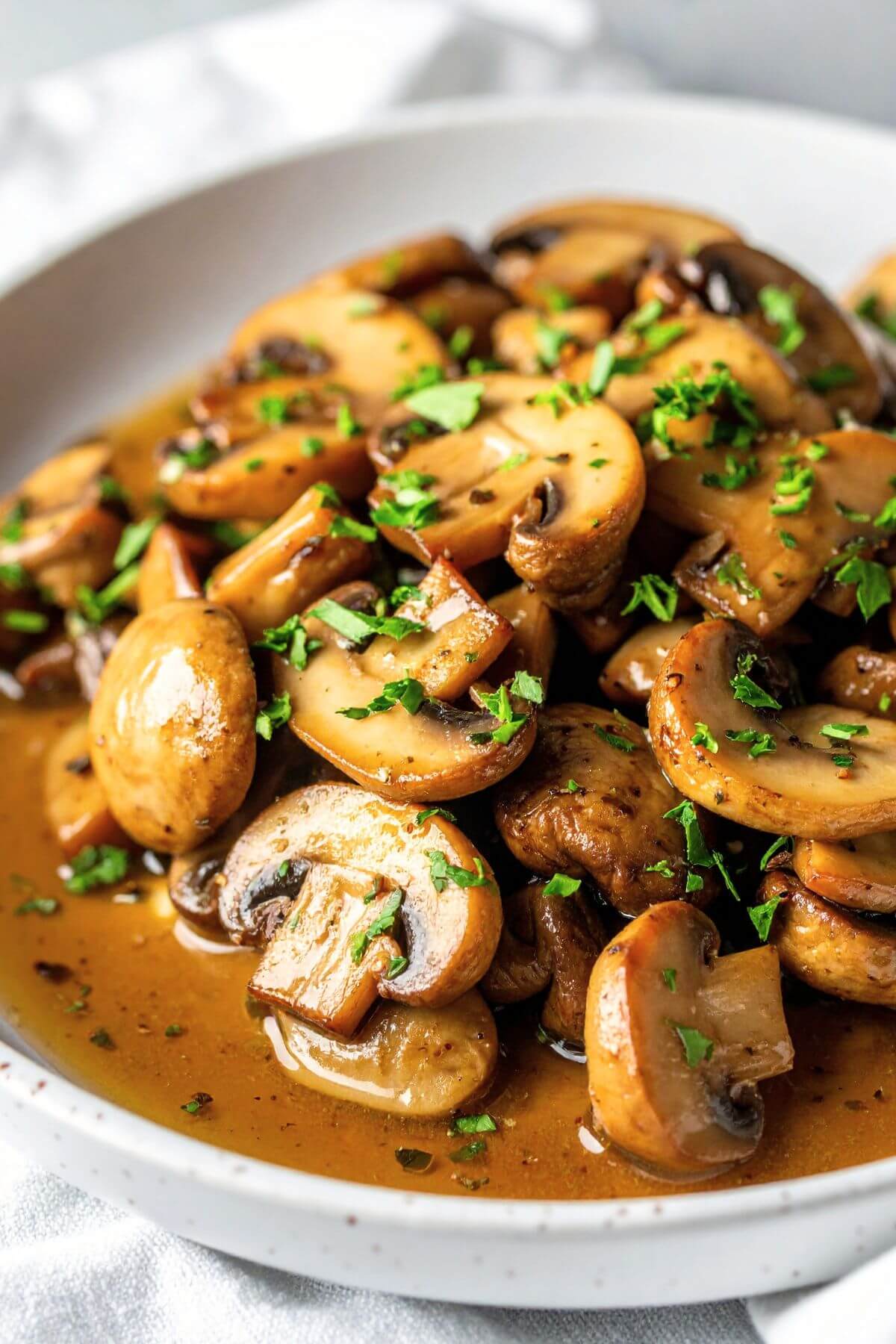 vegan garlic butter mushrooms in a bowl with fresh parsley minced