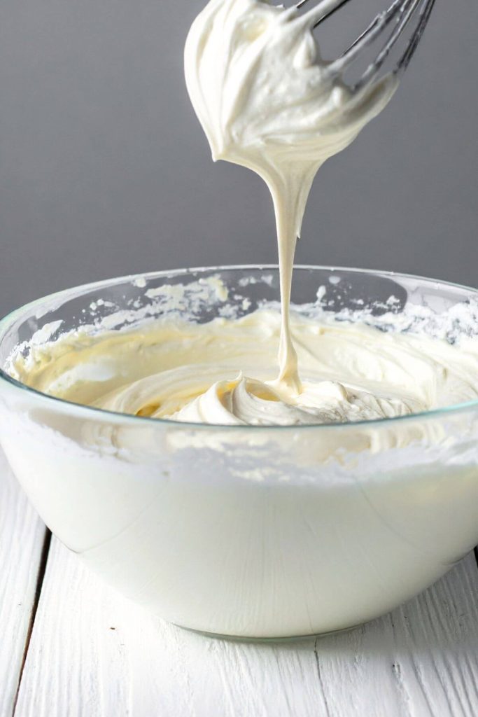 creamy vegan cream cheese frosting dripping from whisk