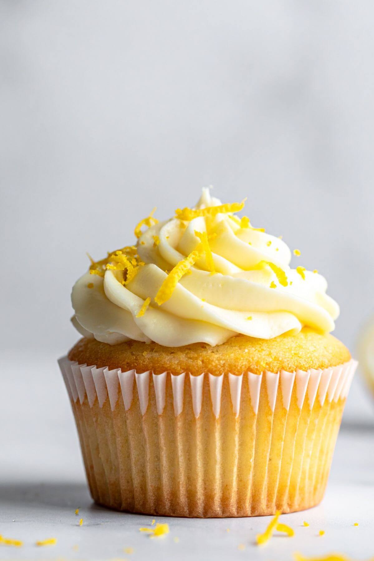 a single vegan lemon cupcake with creamy lemon frosting and fresh lemon zest
