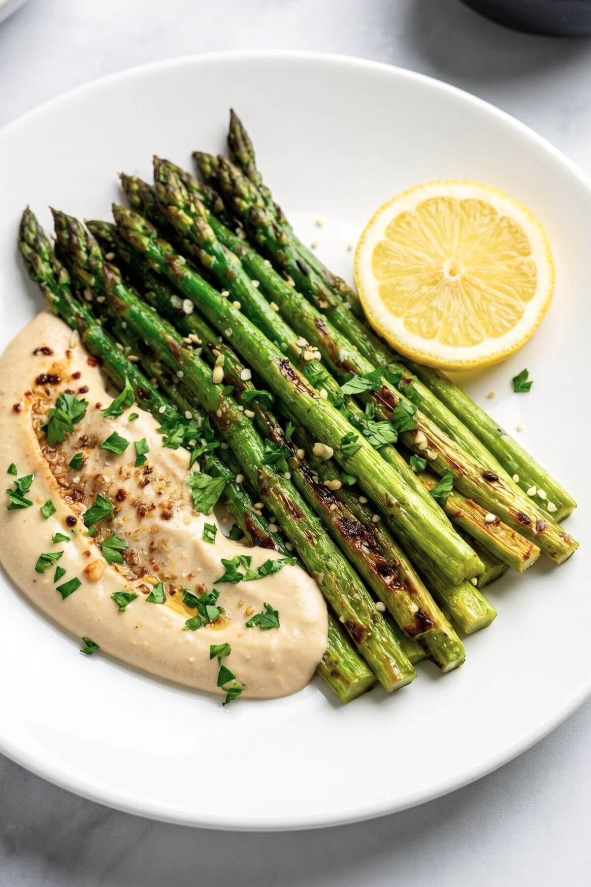 Roasted asparagus spears with tahini sauce and herbs with slice of lemon