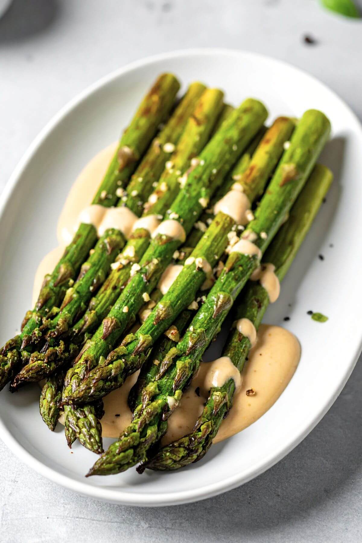 Close-up of roasted garlic asparagus with tahini drizzle
