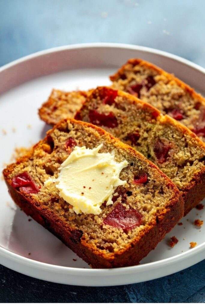 Slice of vegan banana strawberry bread spread with vegan butter on a plate.